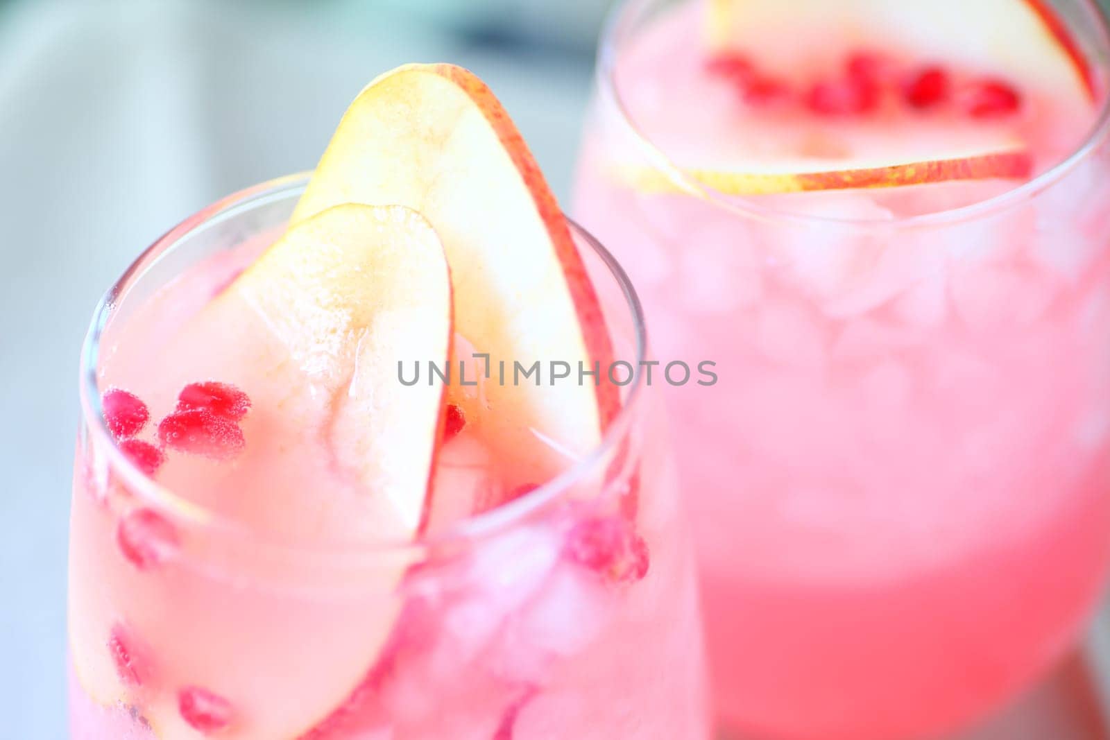 Closeup of two glasses of blush wine with fresh pear slices and pomegranate seeds