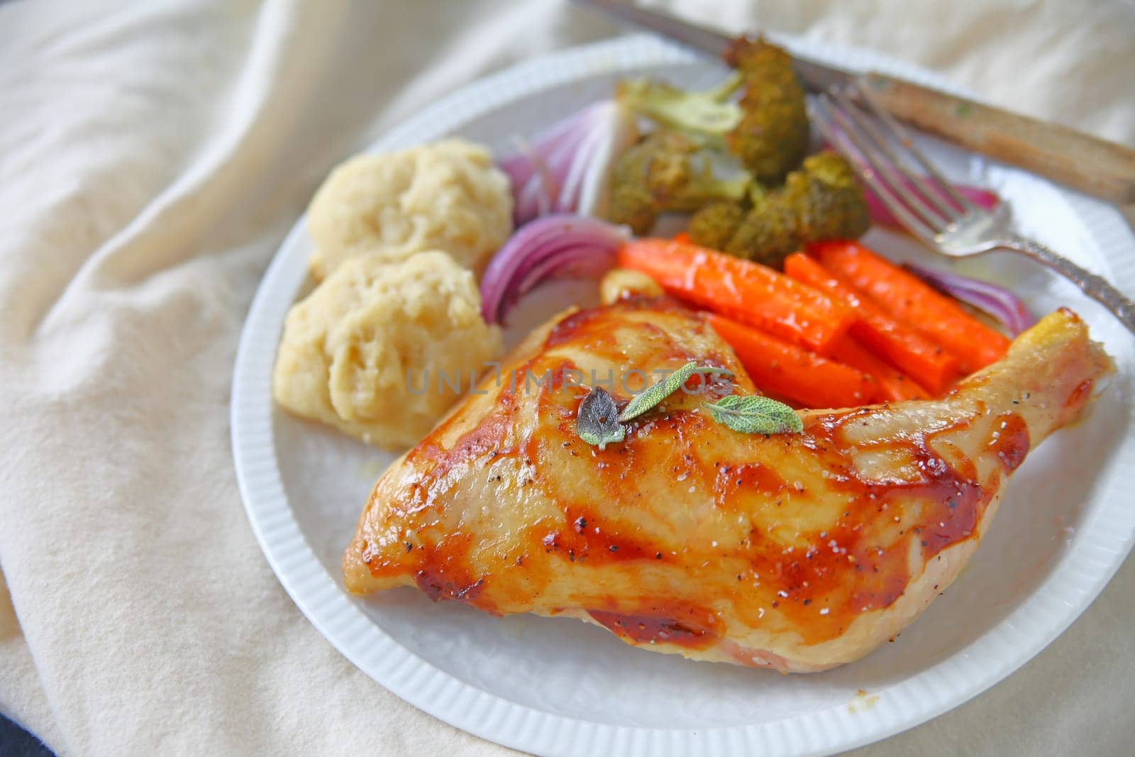 Hoisin sauce glazed chicken quarter with carrots, broccoli, onions and drop biscuits