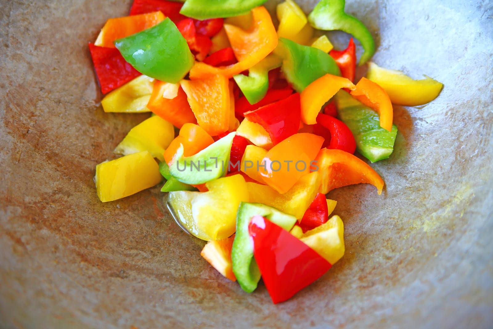 Overhead of wok with red, green yellow and orange bell pepper pieces