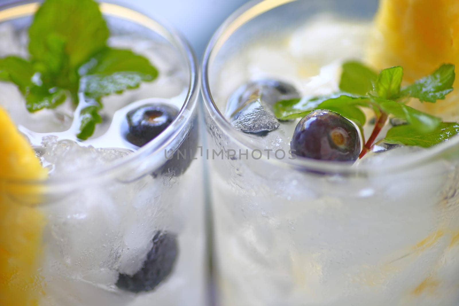 Two wine cocktails with fresh blueberries, pineapple and mint in natural light