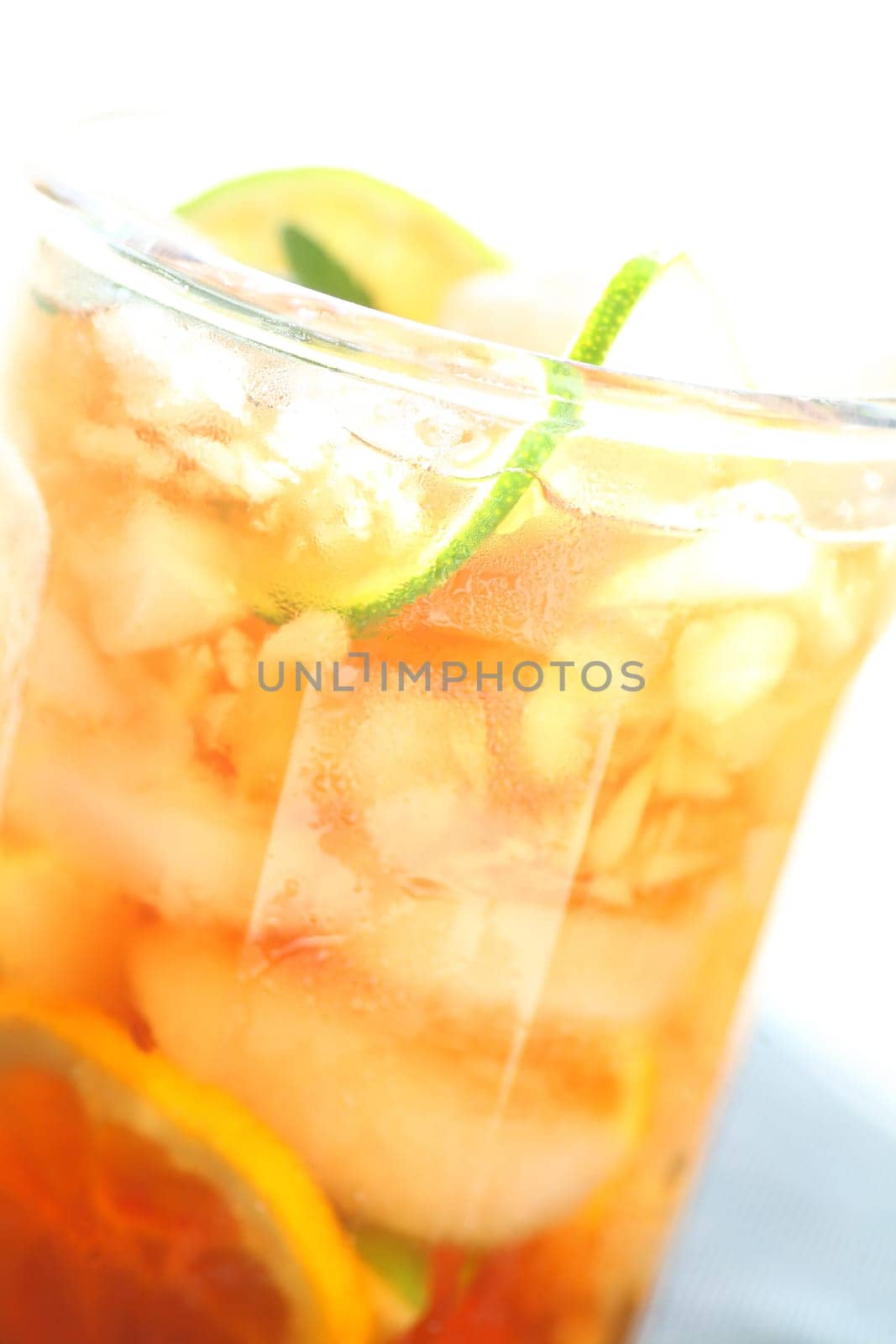 Closeup of a glass of iced tea with lime and lemon slices over ice