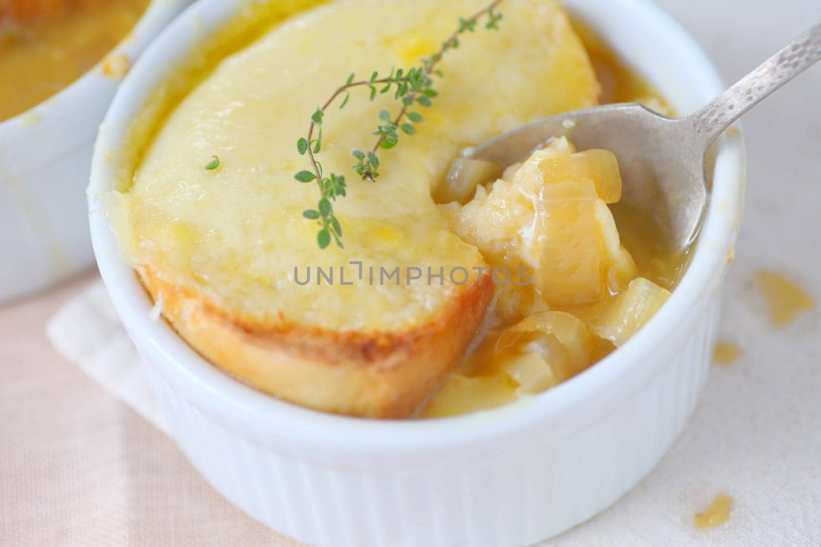 Small bowl of onion soup with melted cheese toast and fresh thyme sprigs on top