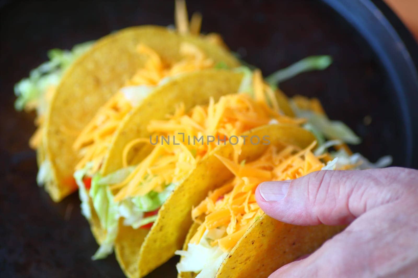 A man with several homemade tacos topped with grated cheese