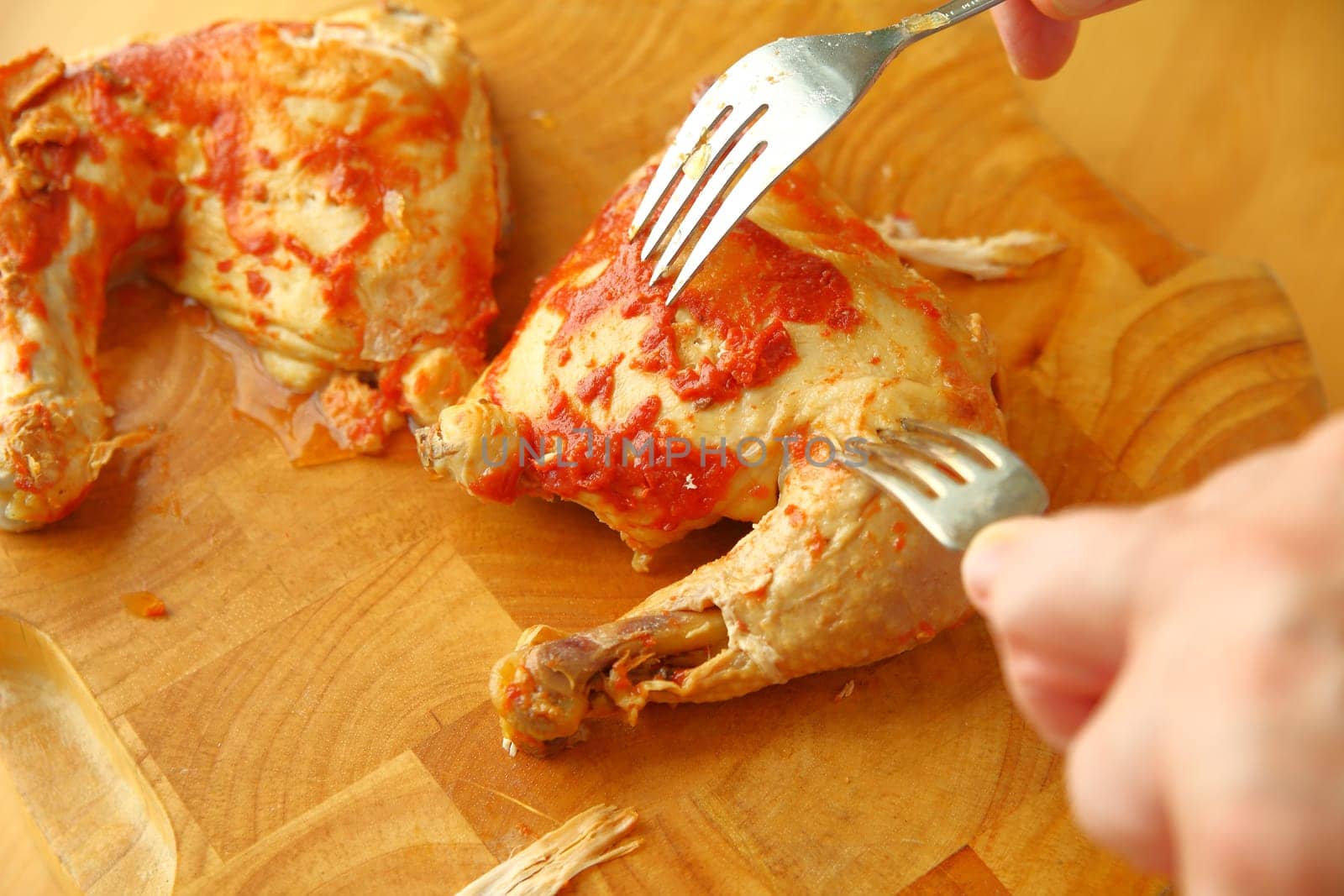 A man uses two forks to make pulled chicken with barbecue sauce