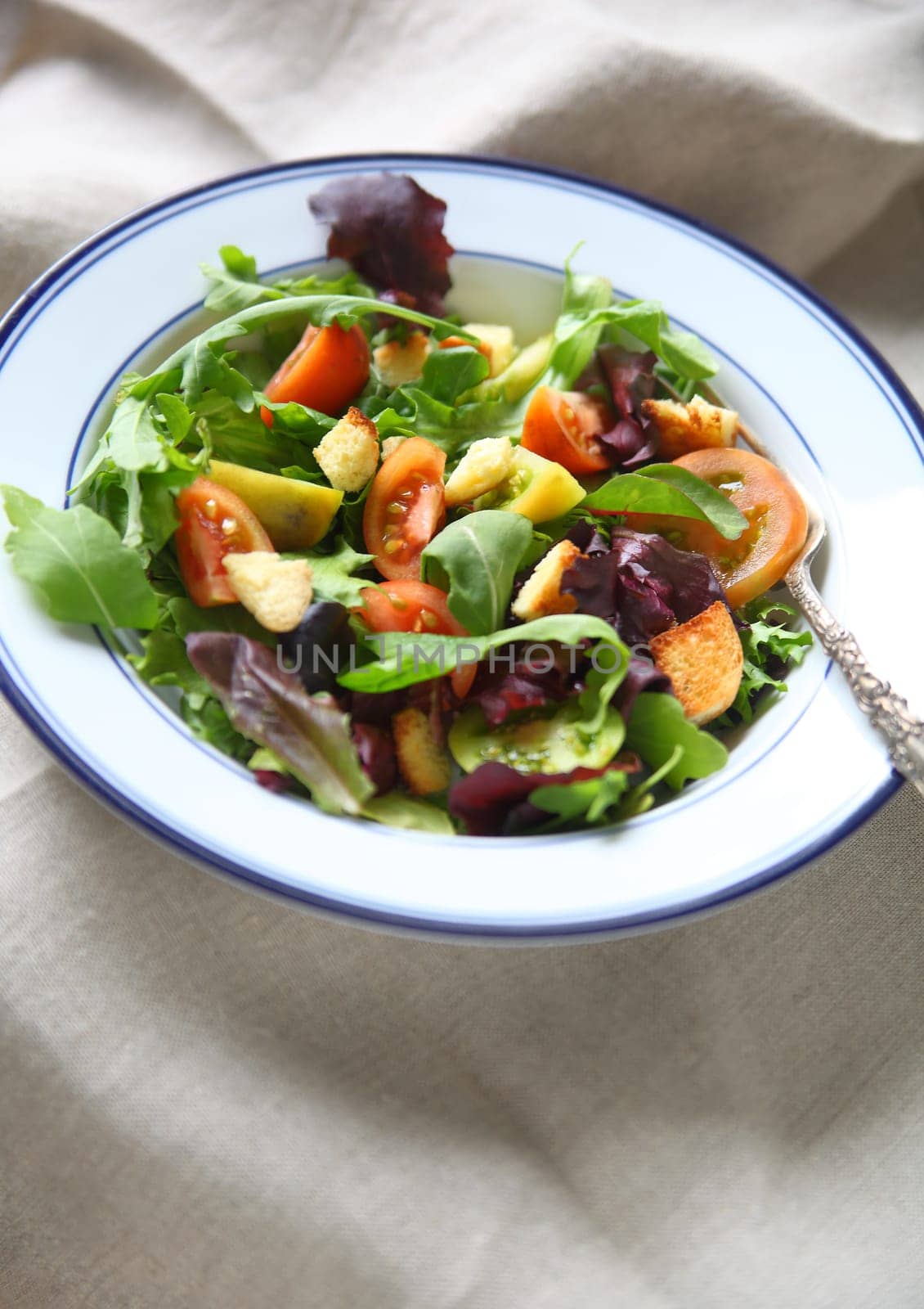 Salad with baby heirloom tomatoes and croutons on a beige napkin with copy space