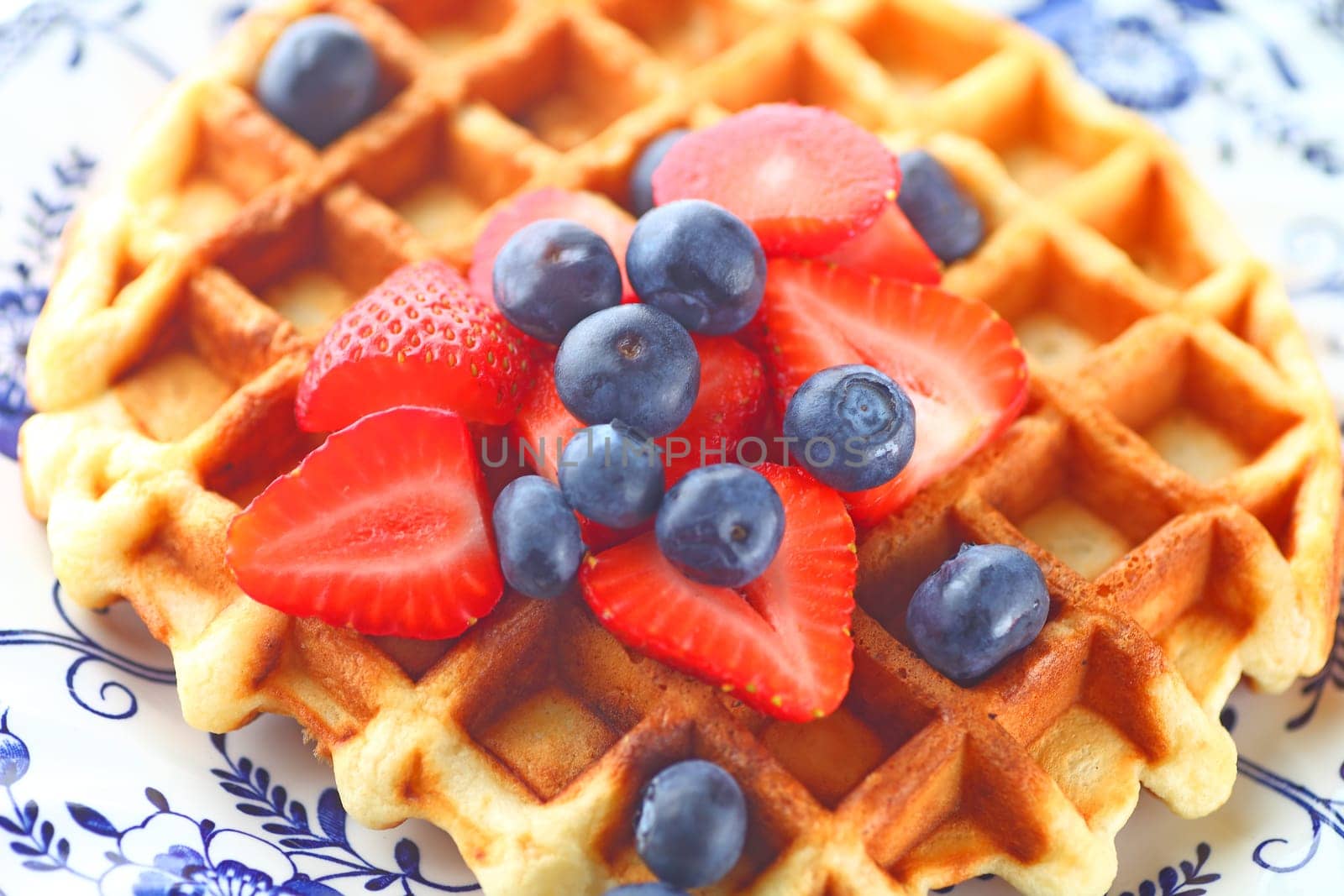Overhead view of homemade waffle topped with fresh blueberries and strawberries