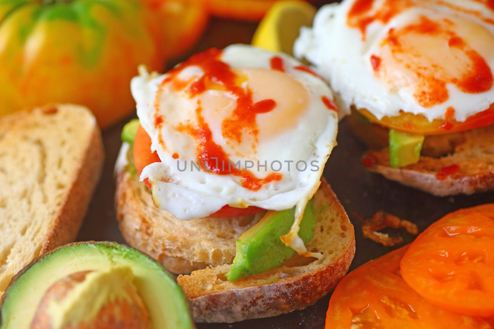 Fried eggs topped with hot chili sauce on avocado toast