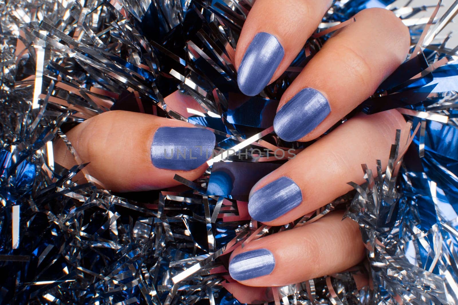 Female hand with blue nails is on texture background. Manicure concept.