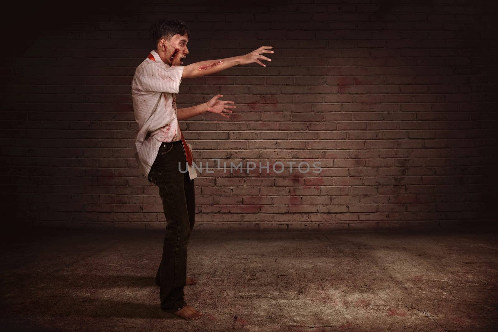 Spooky asian zombie man with claw hand walking against dirty wall background