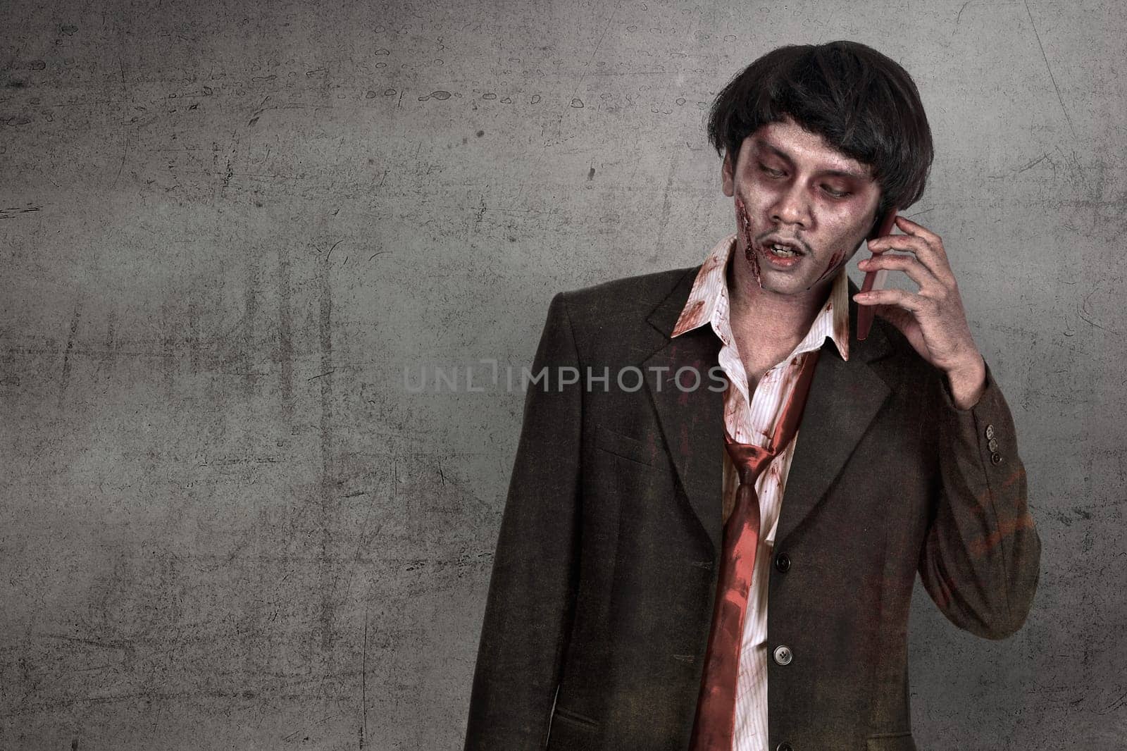 Portrait of creepy asian zombie man in suit call via cellphone