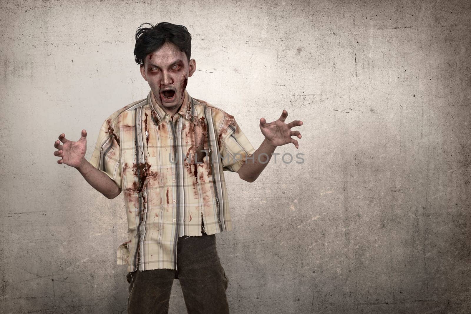 Portrait of asian zombie man with blood standing over grunge background