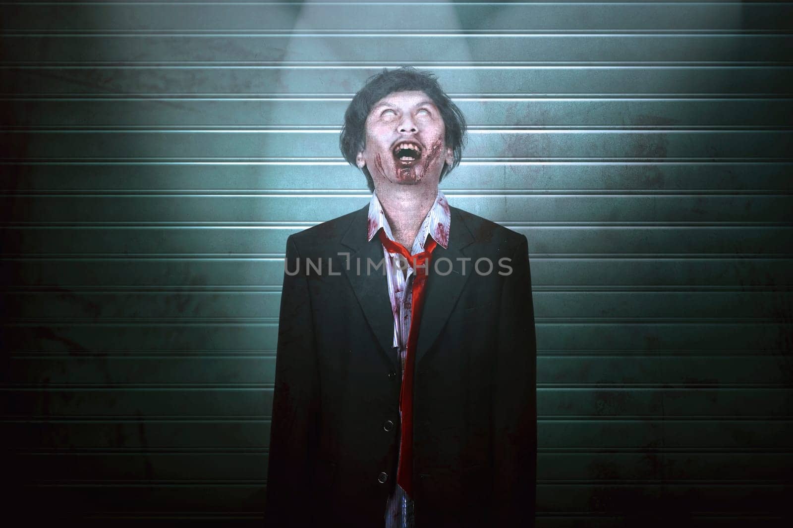 Portrait of creepy asian zombie man in suit standing over rolling door