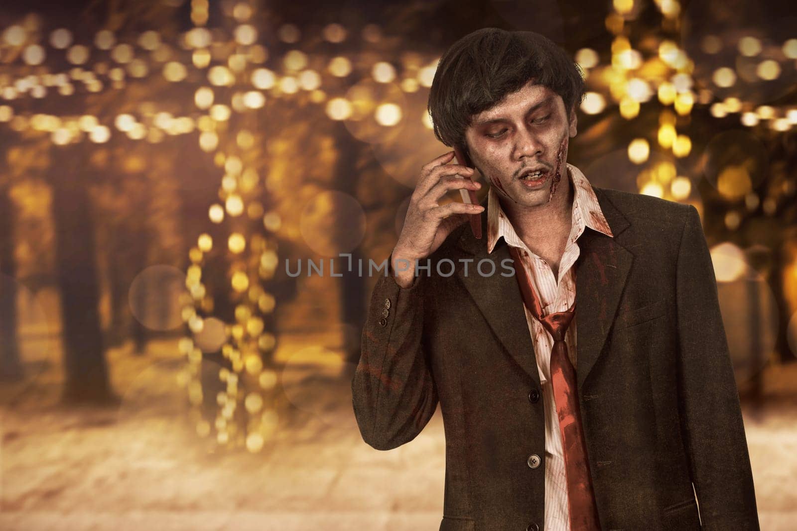 Portrait of creepy asian zombie man in suit call via cellphone