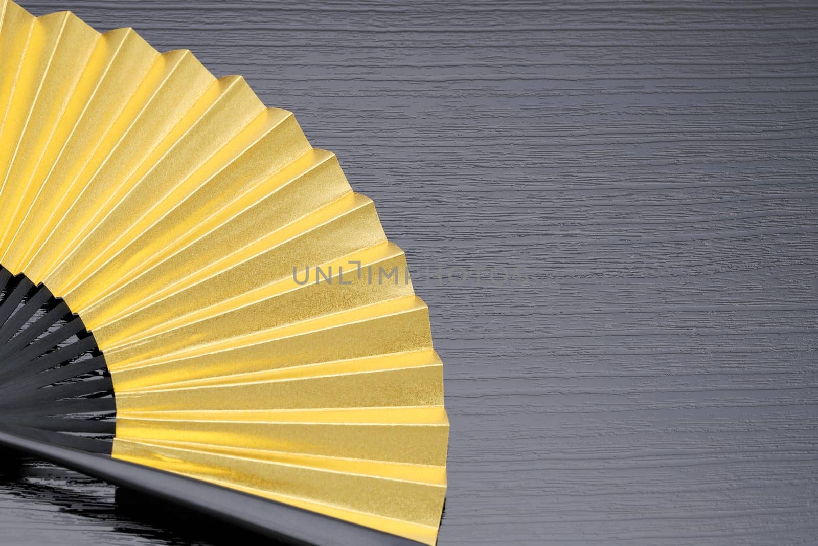 traditional japanese style golden hand fan on gray background