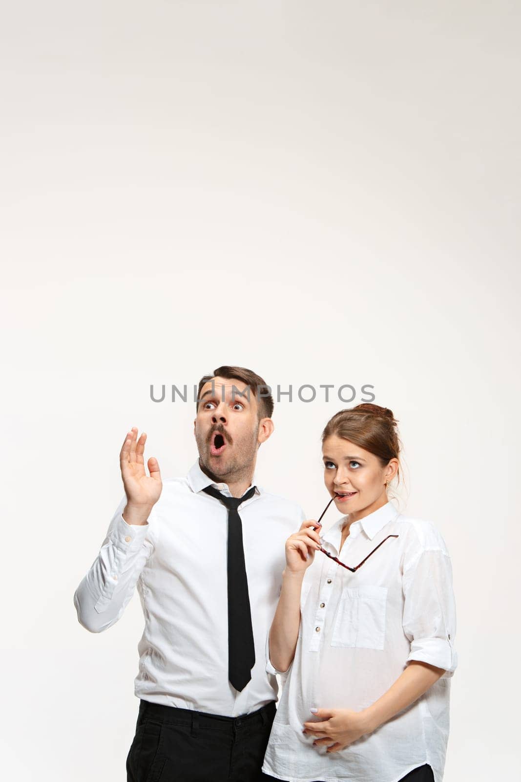 Successful surprised business couple at the office looking up on white background