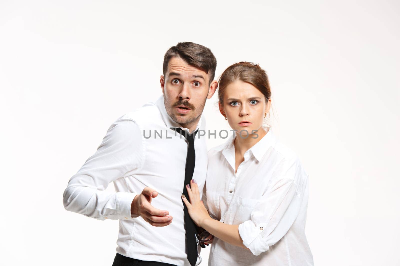 Successful surprised business couple at the office looking at camera on white background