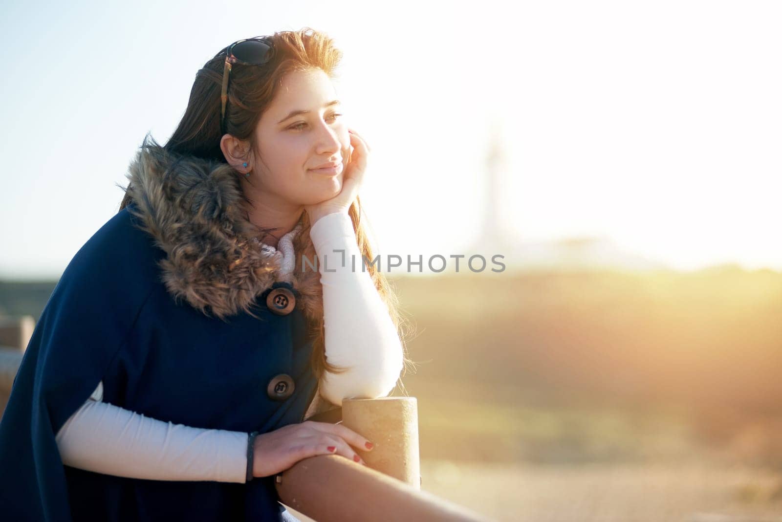 Beautiful happy young girl posing outdoors at sunset near a lighthouse