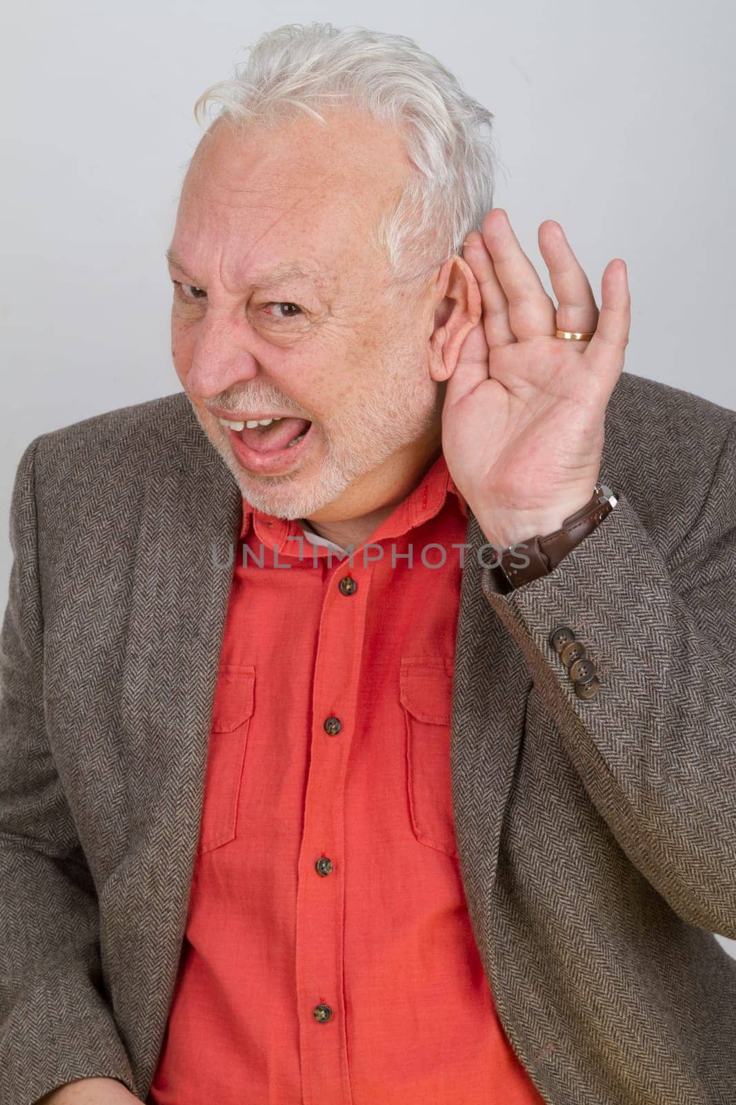 Hearing impaired senior holds hand to ear on a bright background