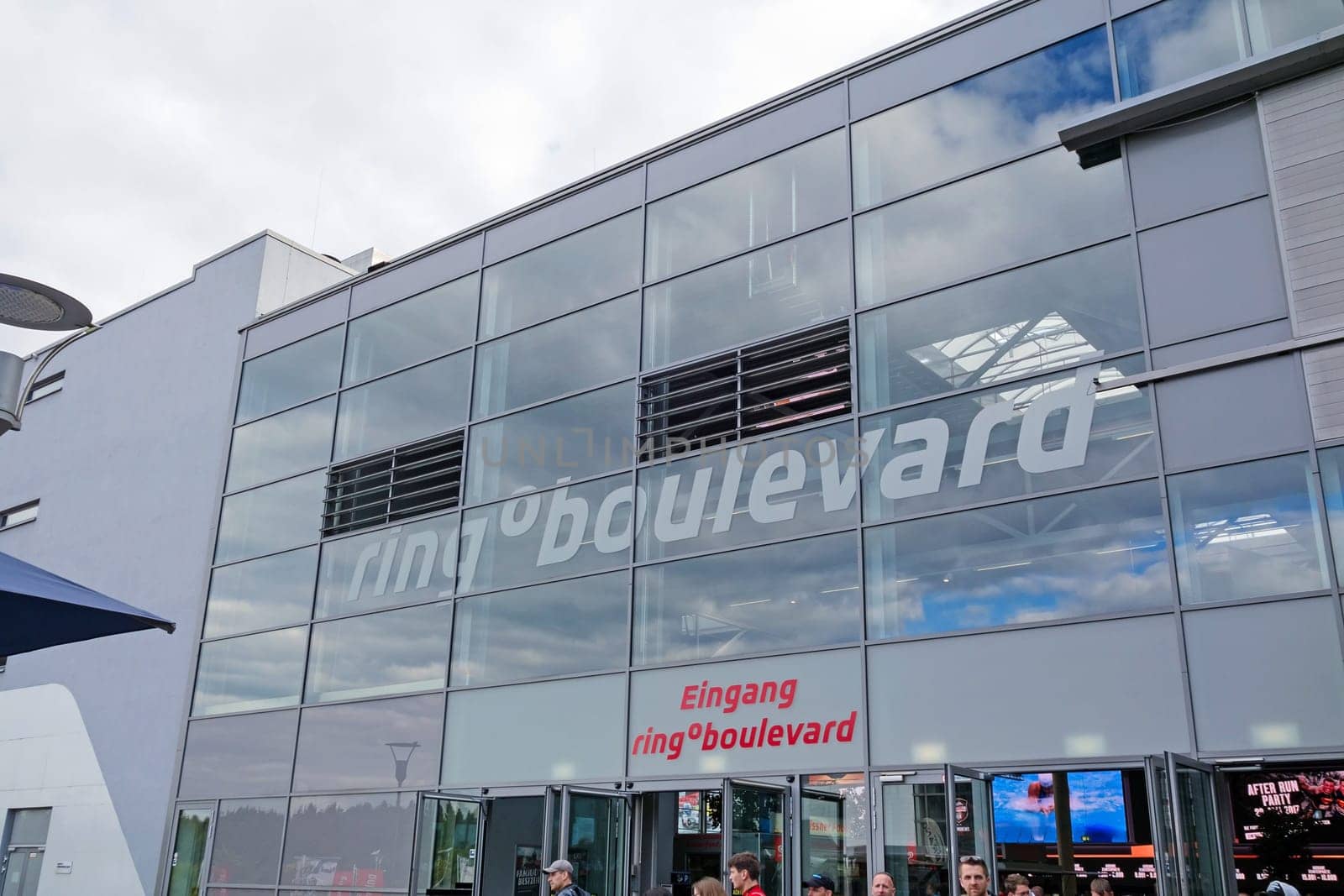 Nurburg, Germany - May 20, 2017: Race track Nurburgring, people in front of entrance "ring boulevard"" - glass facade building"