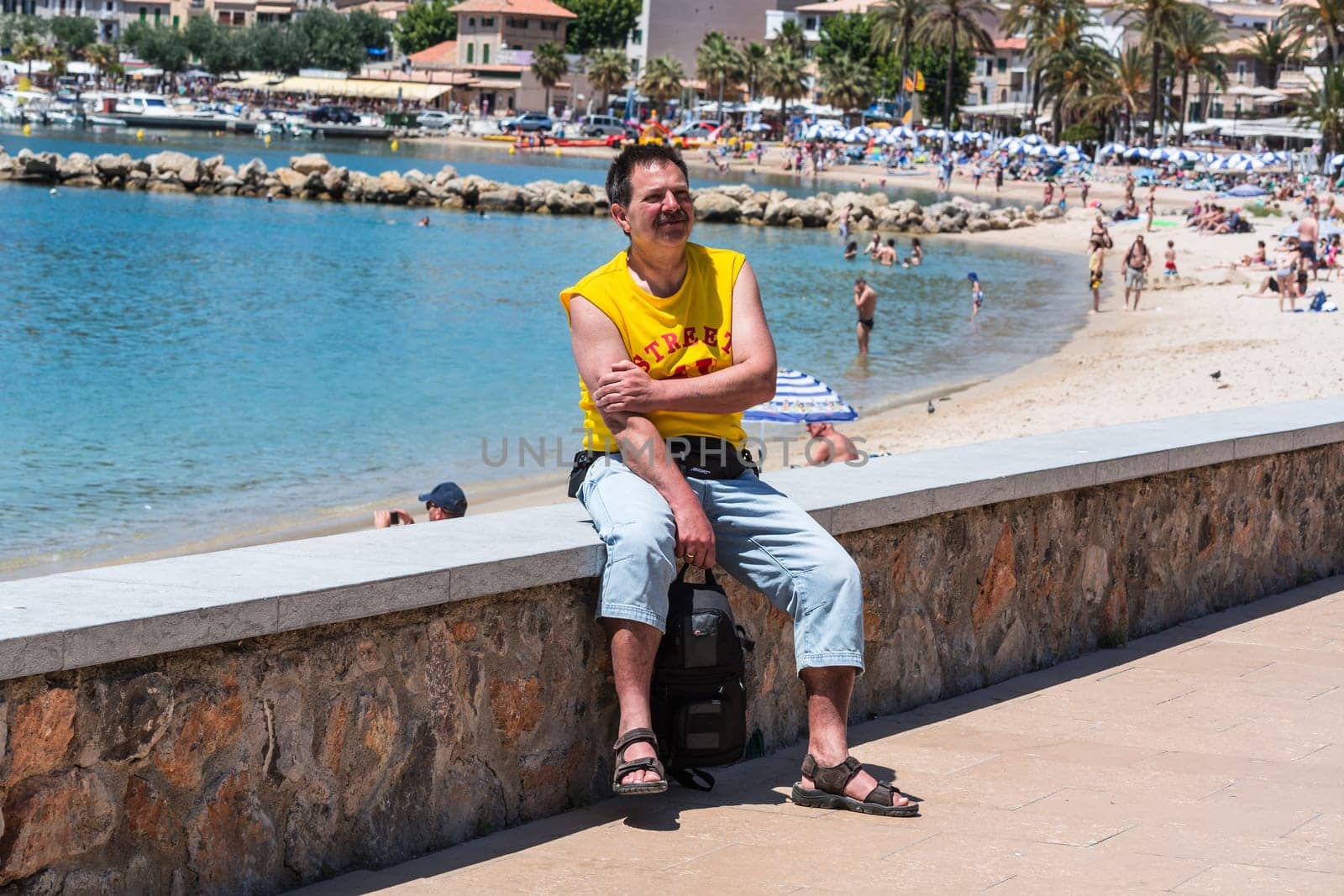 PORT DE SOLLER, SPAIN - JUNE 02, 2016:.Tourist on the wall of the beach promenade of Port de Soller in Mallorca, Spain.