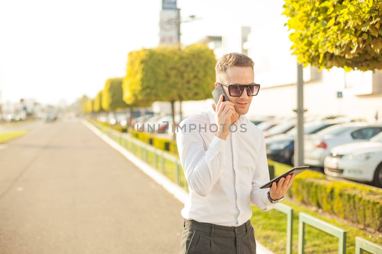 Businessman Man With Mobile Phone and Tablet computer in hands, In City, Urban Space