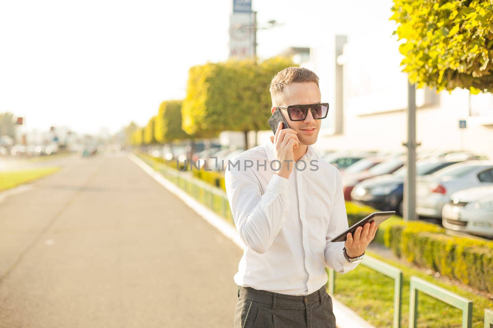 Businessman Man With Mobile Phone and Tablet computer in hands, In City, Urban Space