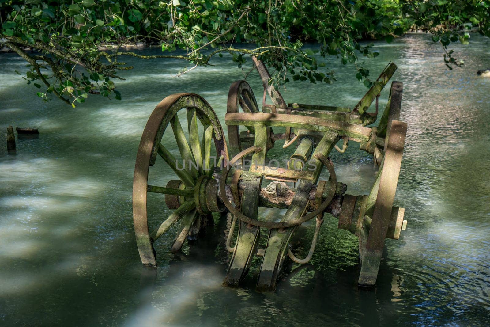 Old wooden wagon, rusty and broken, stranded in a waterhole