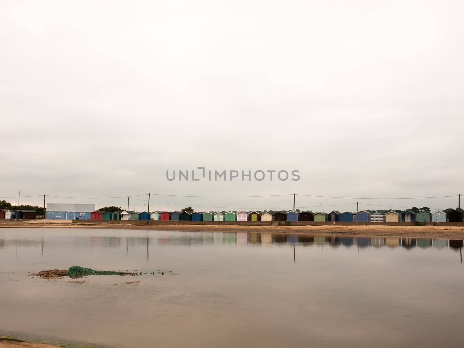 beautiful scene of beach huts with reflections in water in front  England  UK