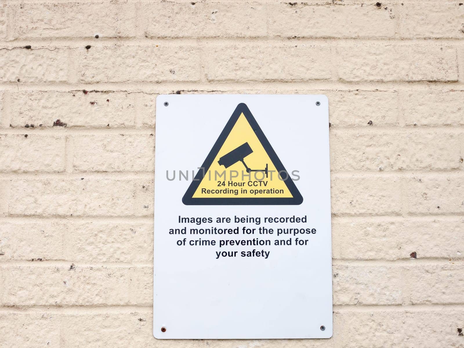 a white placard sign on wall surveillance cctv warning  England  UK