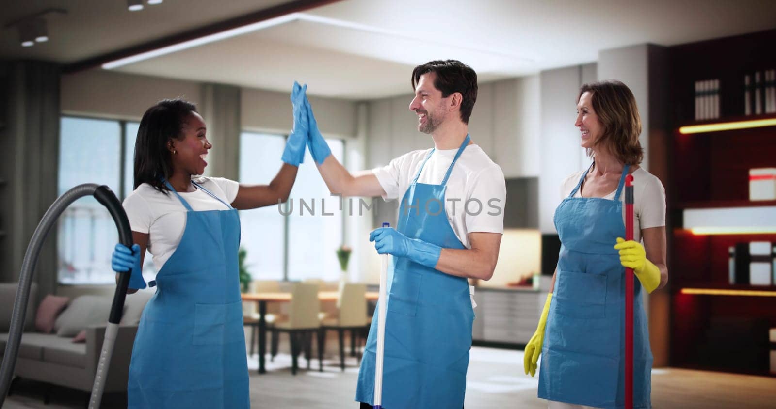 Group of janitors working together, giving high five in kitchen.