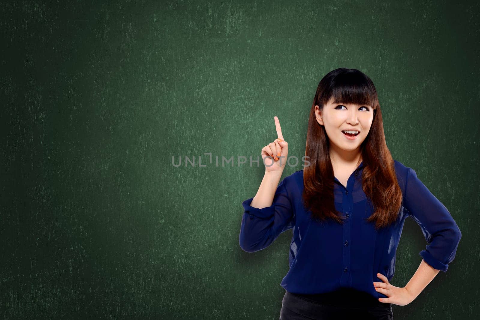 Pretty asian woman pointing empty space with confidence over chalkboard background