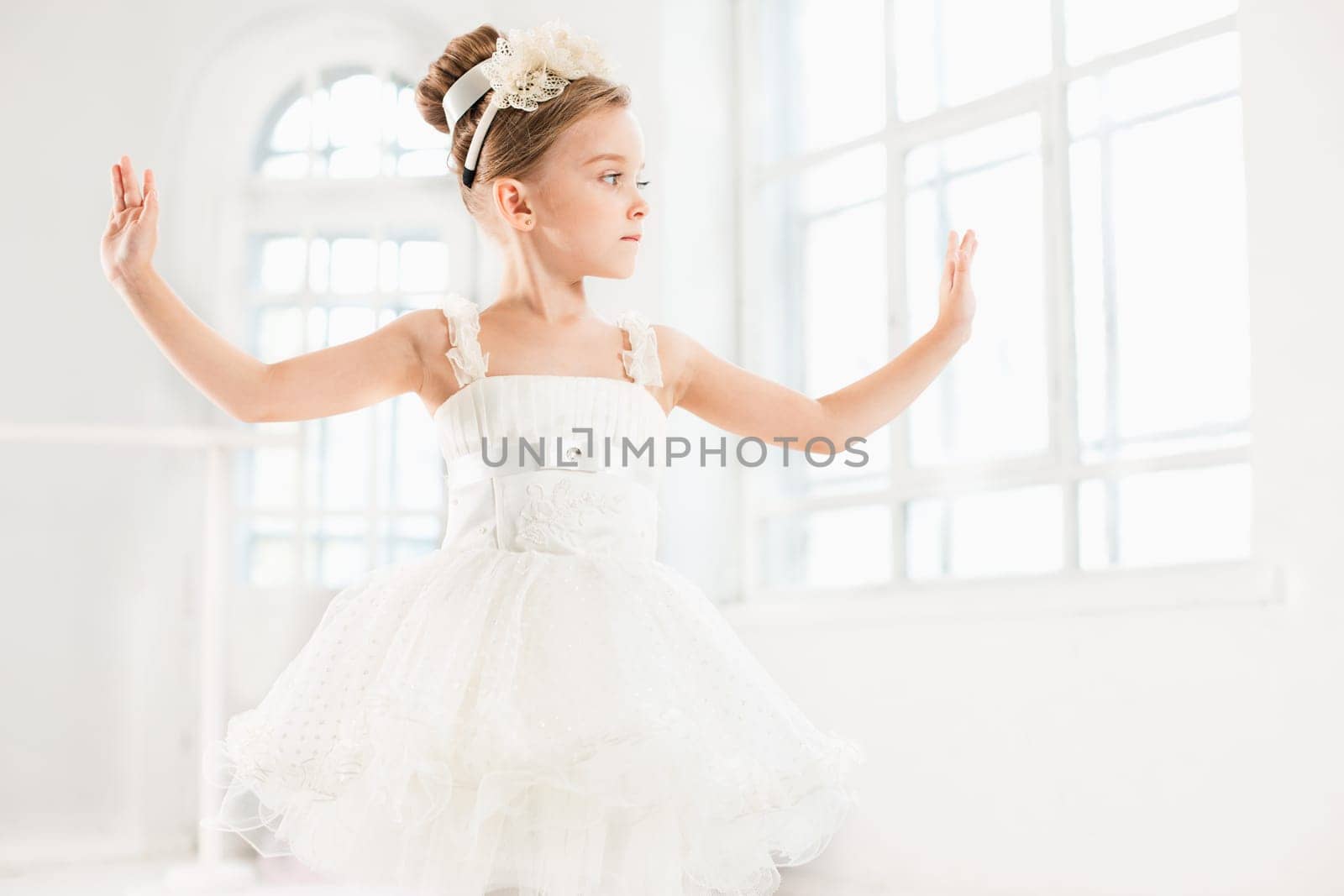 Little ballerina girl in a tutu. Adorable child dancing classical ballet in a white studio. Children dance. Kids performing. Young gifted dancer in a class. Preschool kid taking art lessons.