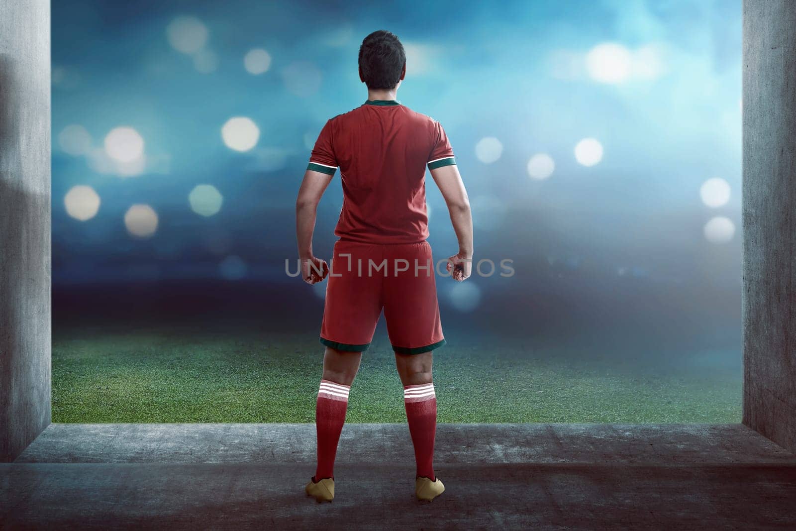 Back view of asian football player standing on hallway to the field