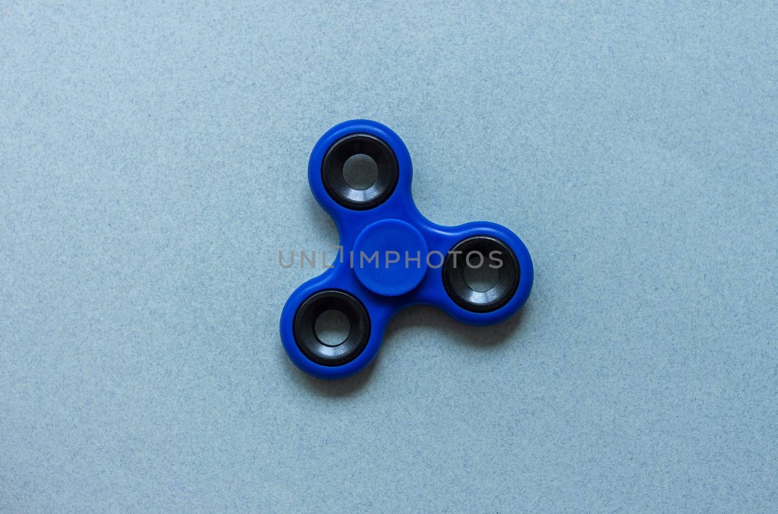 fidget finger spinner stress relief toy on blue paper background