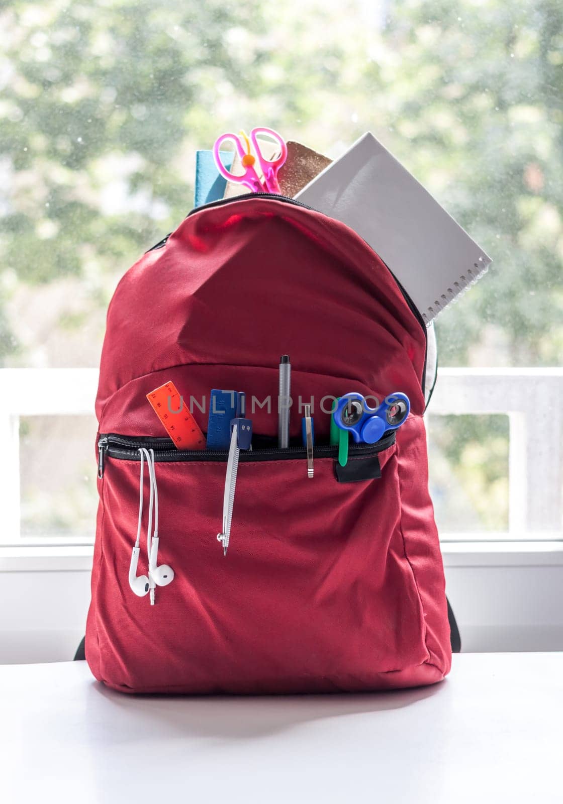 red backpack with school supplies on light background