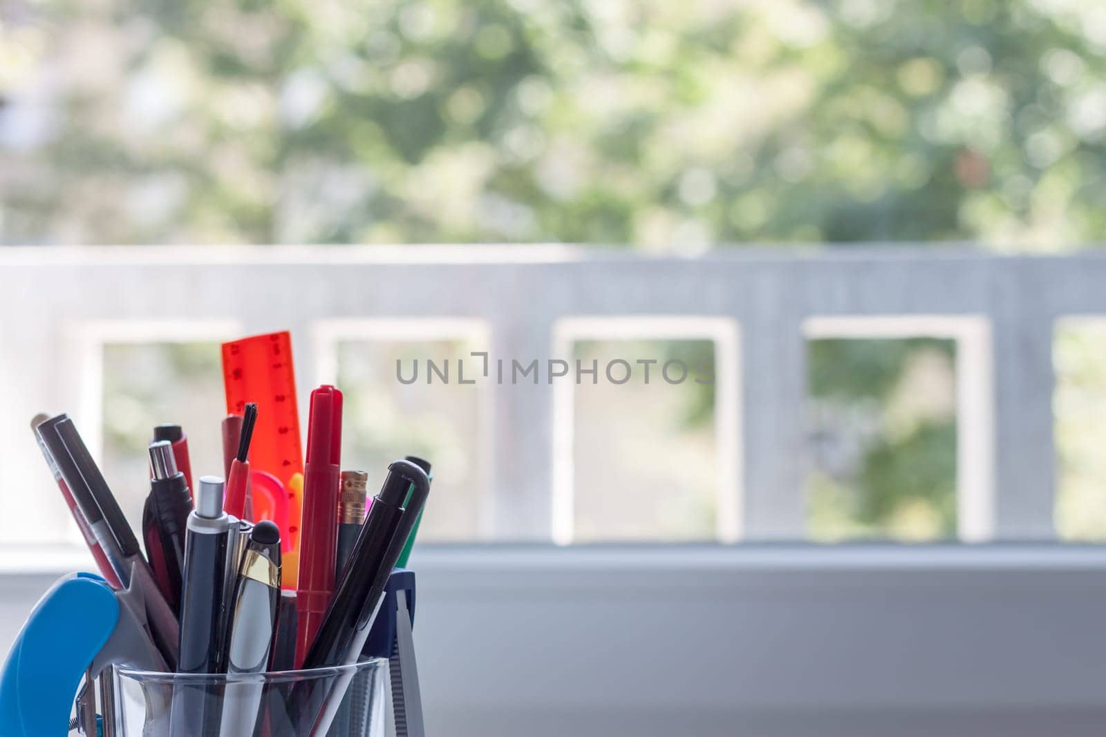 glass with stationery on light blurred background
