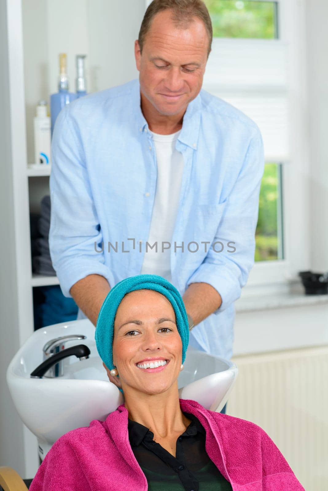 hairdresser washing hair of woman in his shop