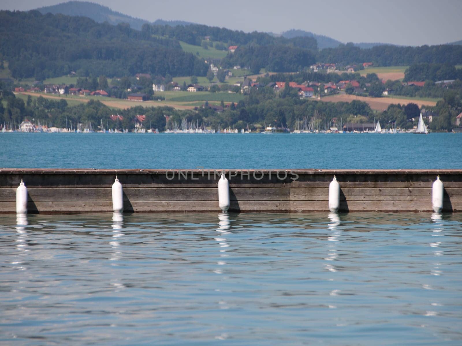 Wooden Pier with Five White Plastic Fenders Hanging on Side