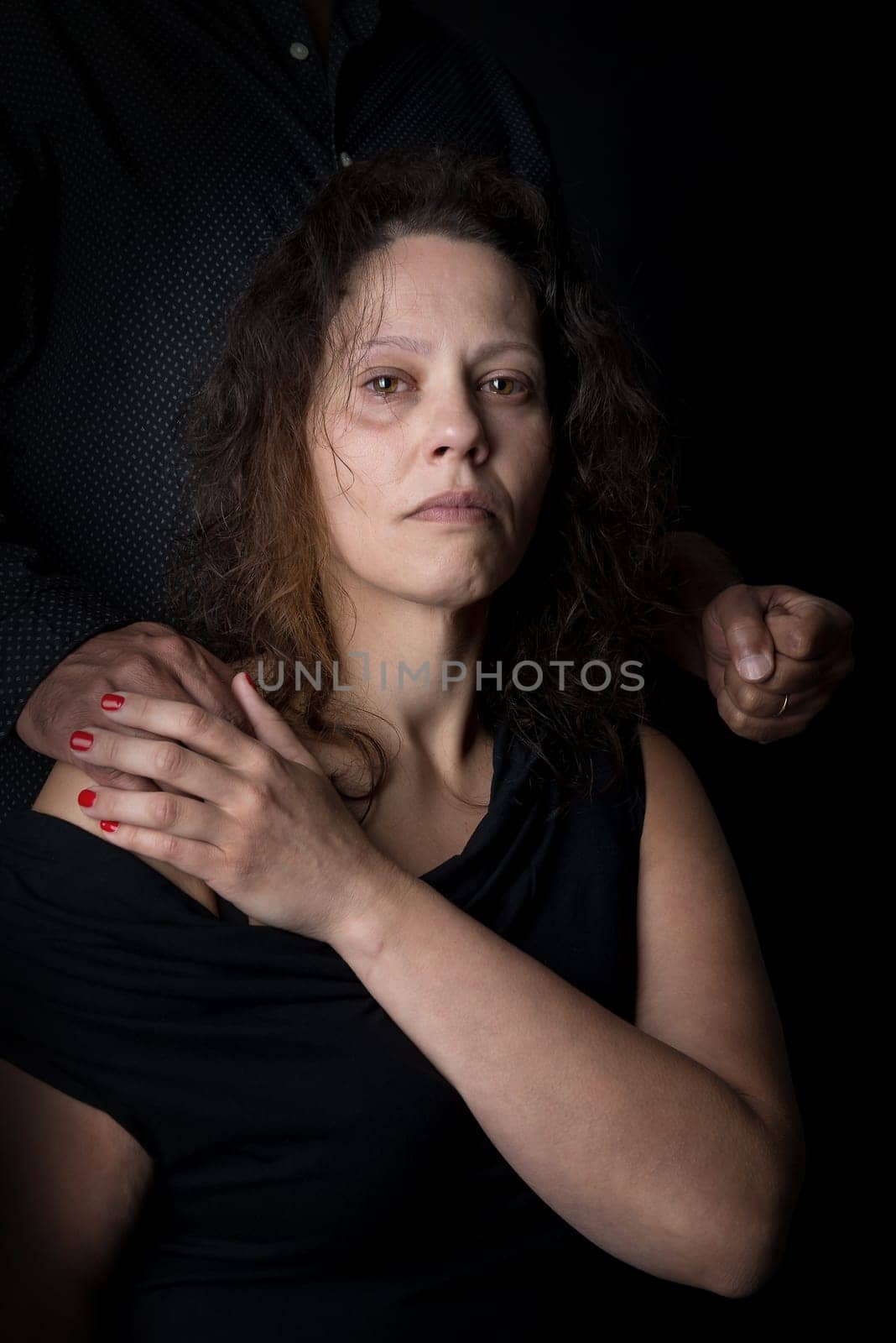 Abused woman victim of domestic violence, with man's fist.