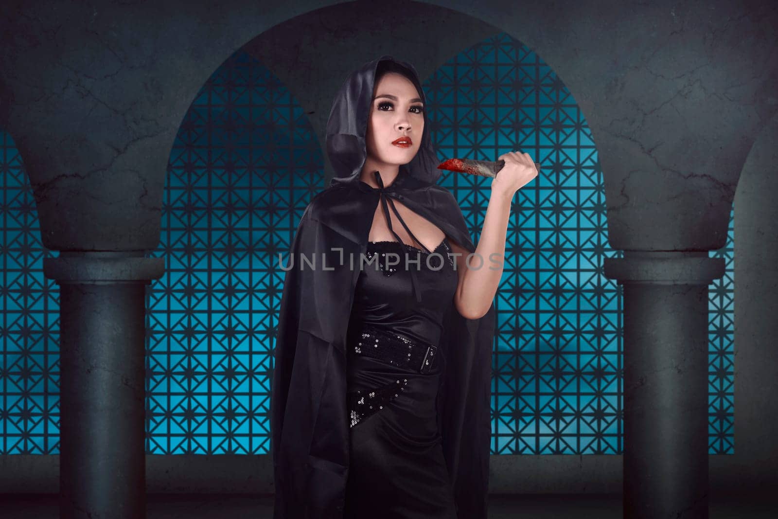 Young beautiful asian witch holding bloody knife on the old building