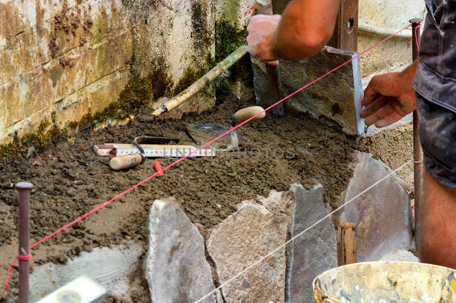 Workers laying and clinkering natural stone slabs.