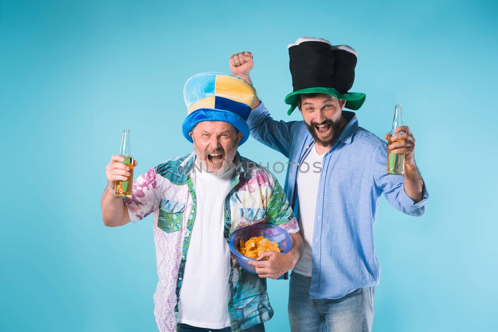 The two emotional football fans over blue background with beer and chips