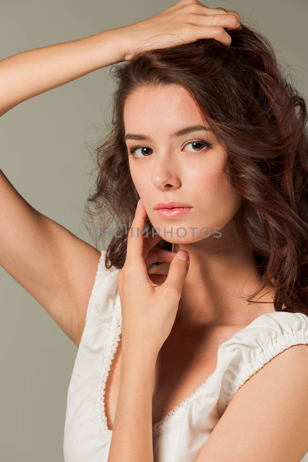 The face of young woman with long hair on gray studio background