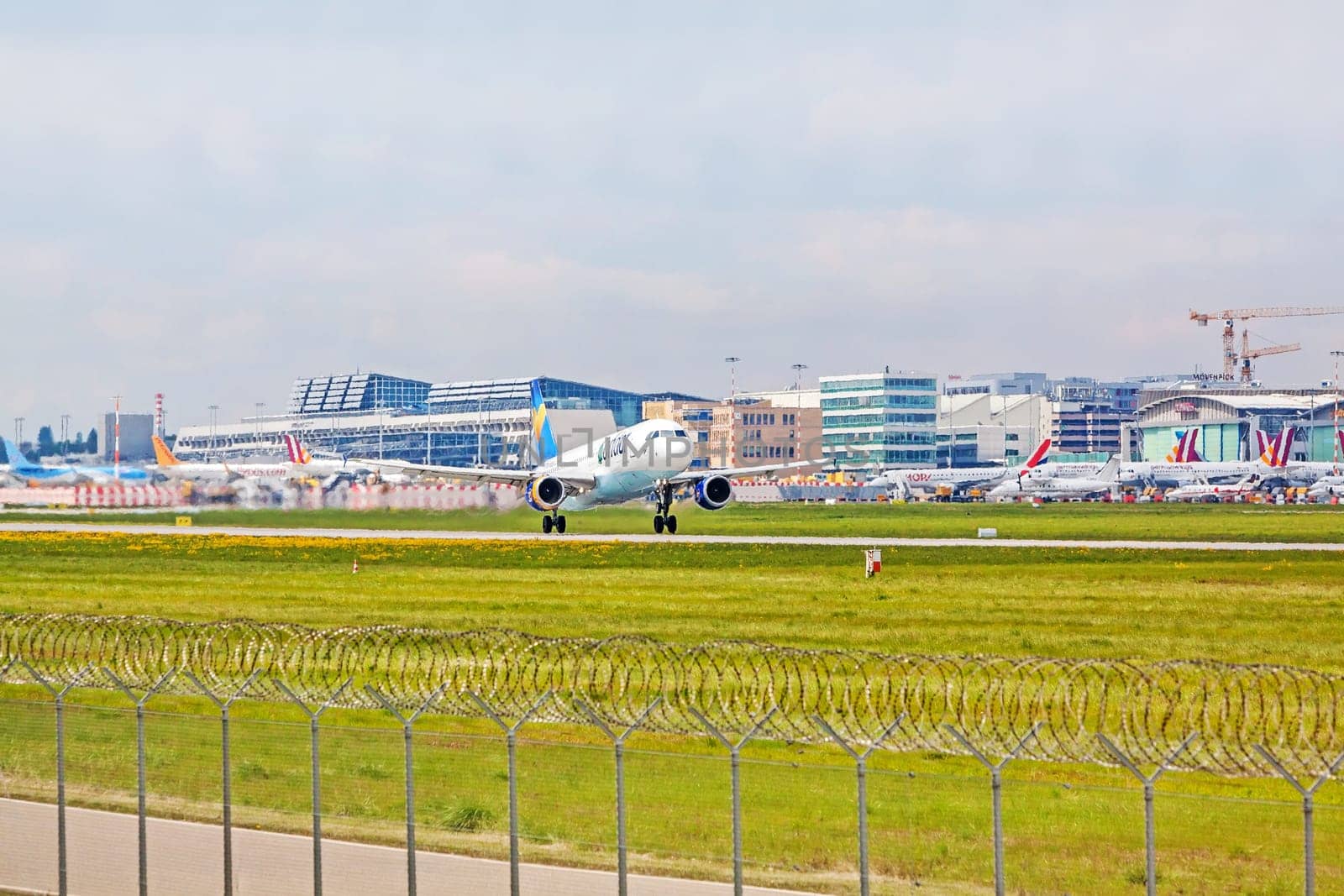 Stuttgart, Germany - April 29, 2017: Airbus airplane A320 from Condor at takeoff from runway - airport Stuttgart terminal in background - green meadow with fence in front