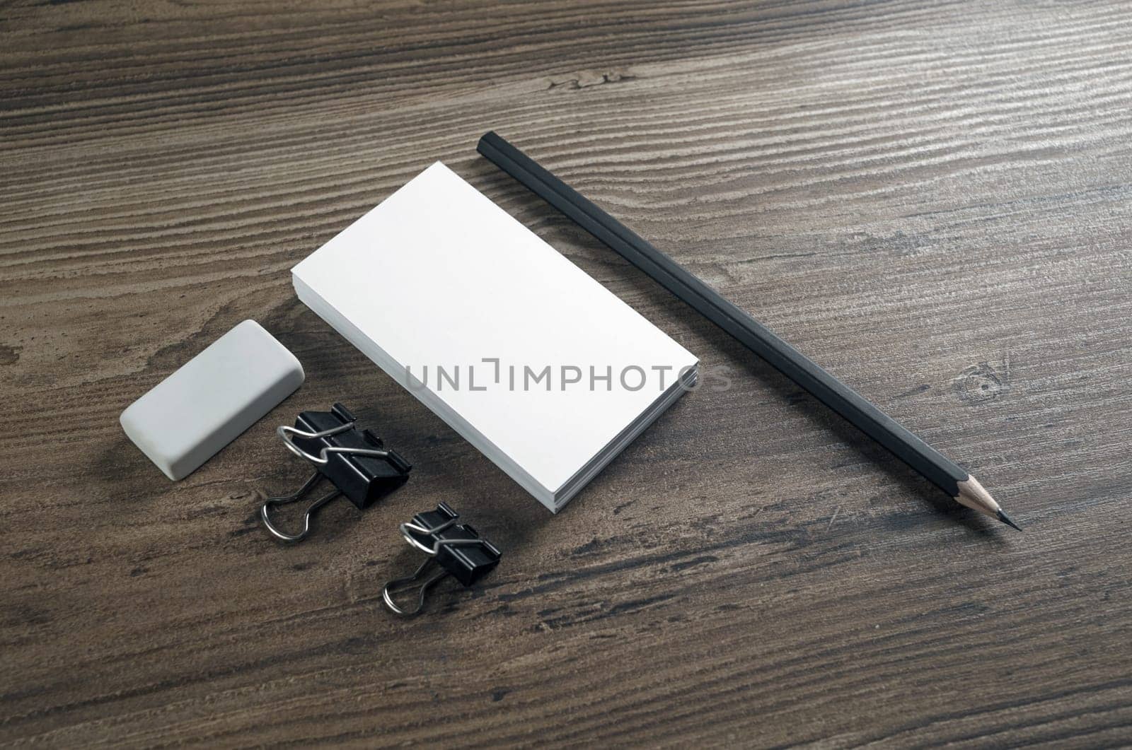 Photo of blank business cards, pencil and eraser on wooden background. Blank stationery set.