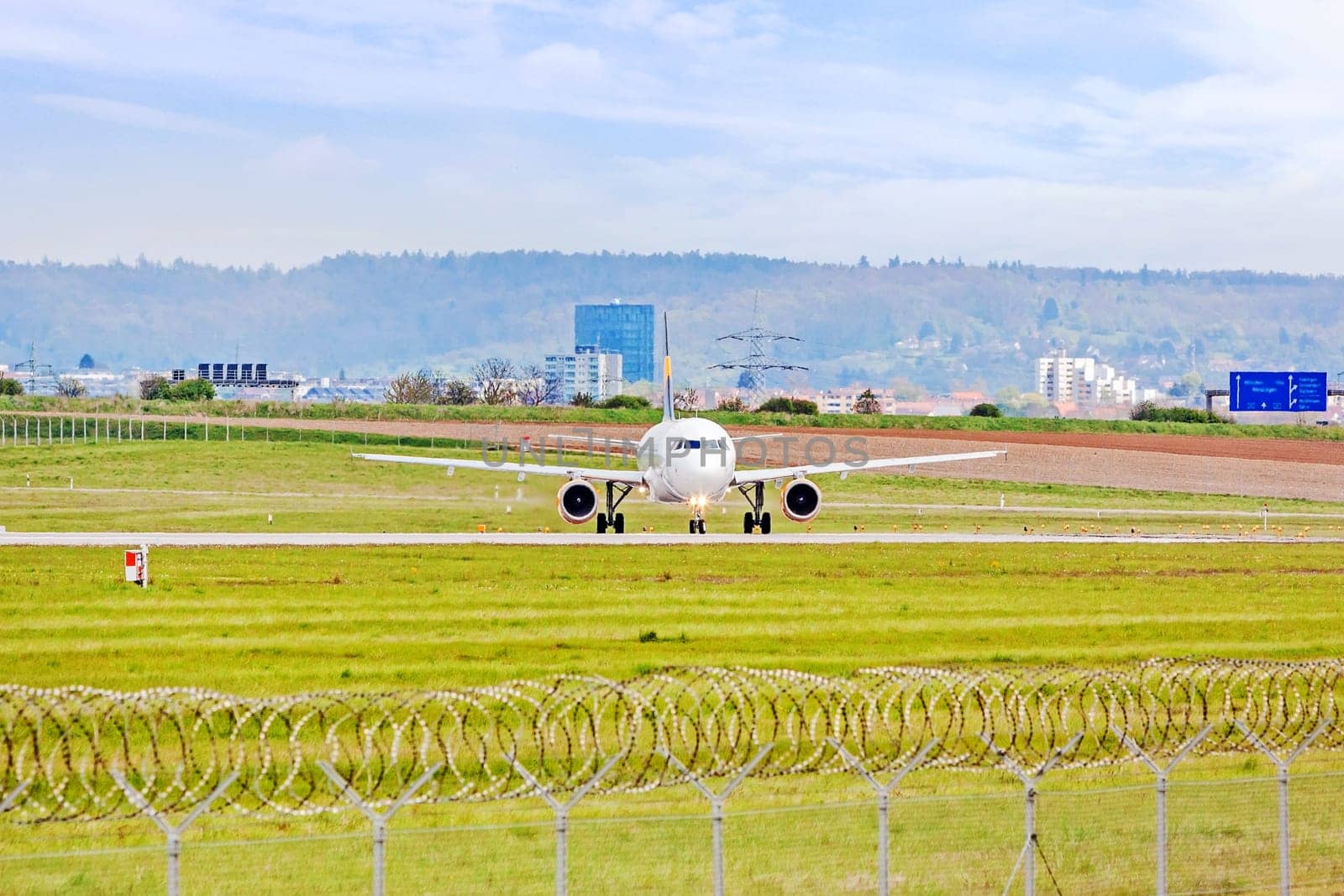 Airplane at ground on its way to runway before takeoff - green meadow with fence in front