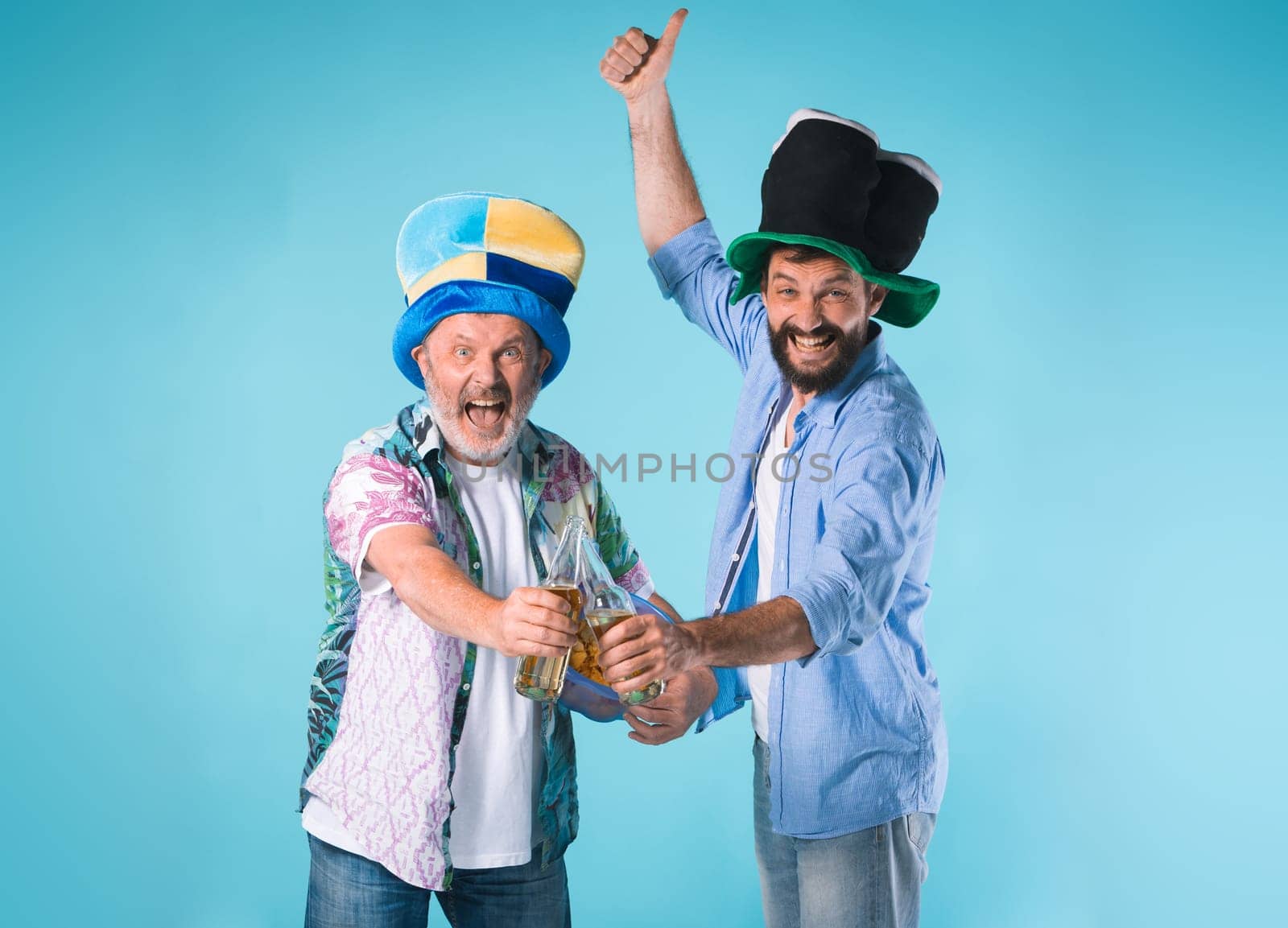 The two emotional football fans over blue background with beer