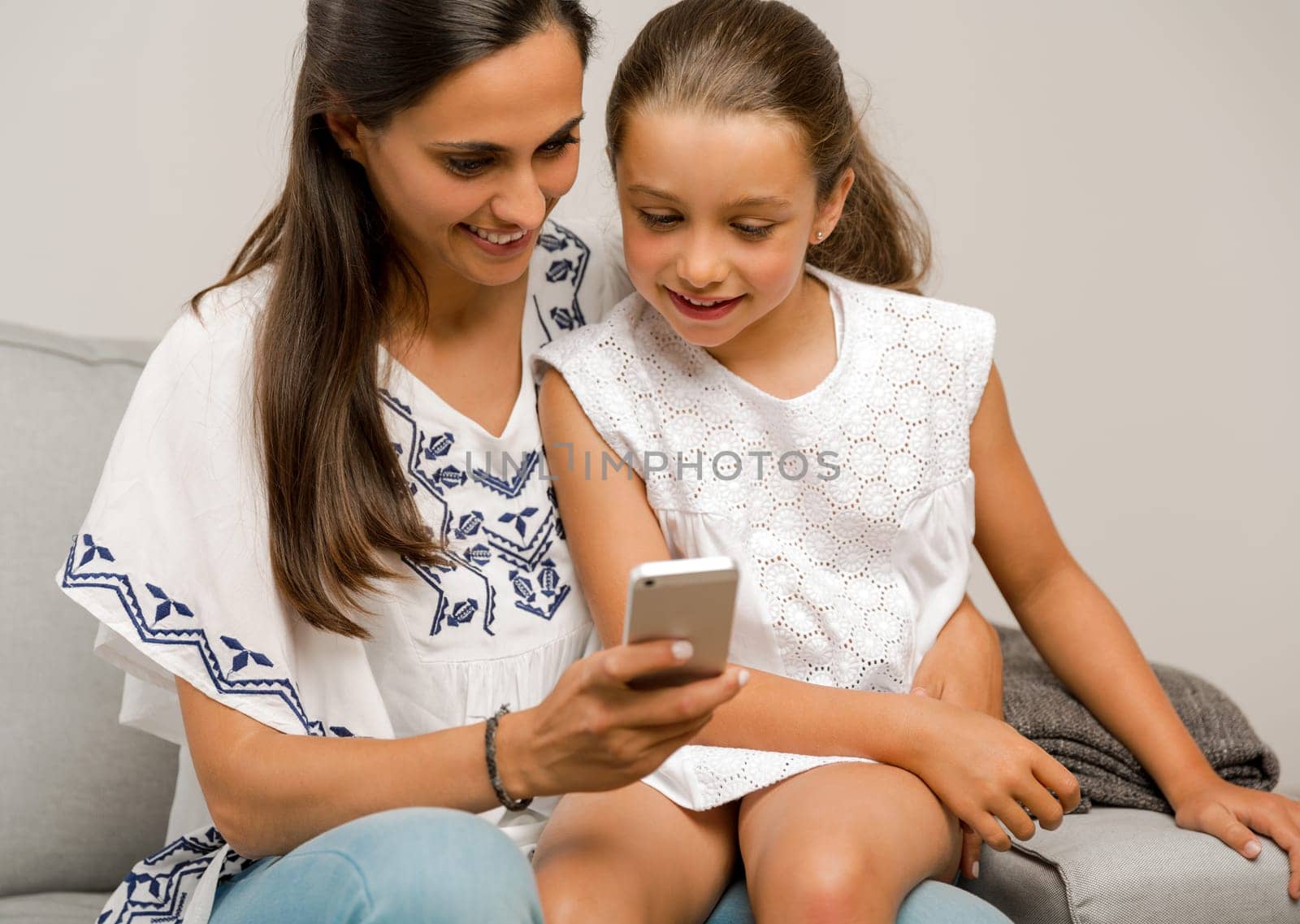 Beautiful Mom and Daughter at home, showing something on the phone