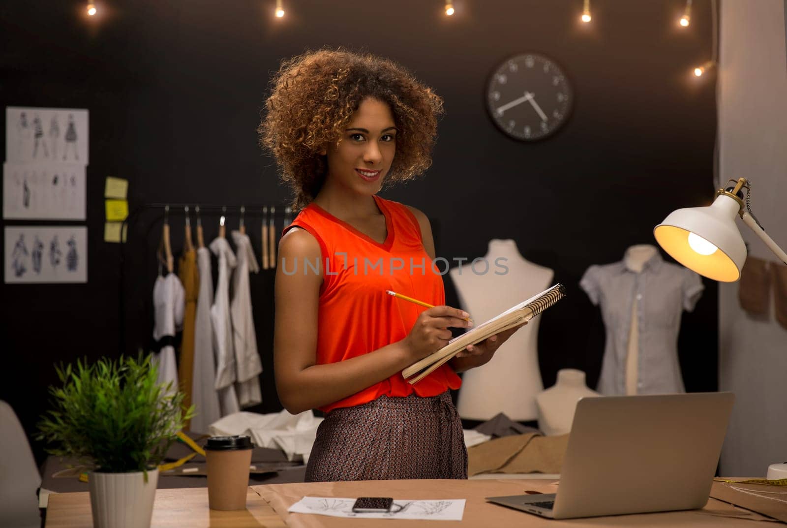 Portrait of a young fashion designer working on her atelier