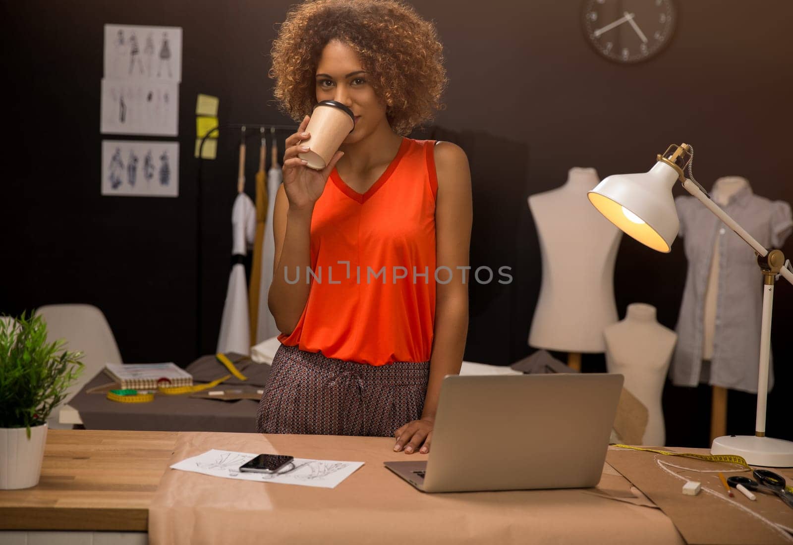 Portrait of a young fashion designer working on her atelier